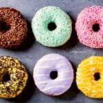 Seis donas con glaseado de colores sobre mesa de mármol gris oscura